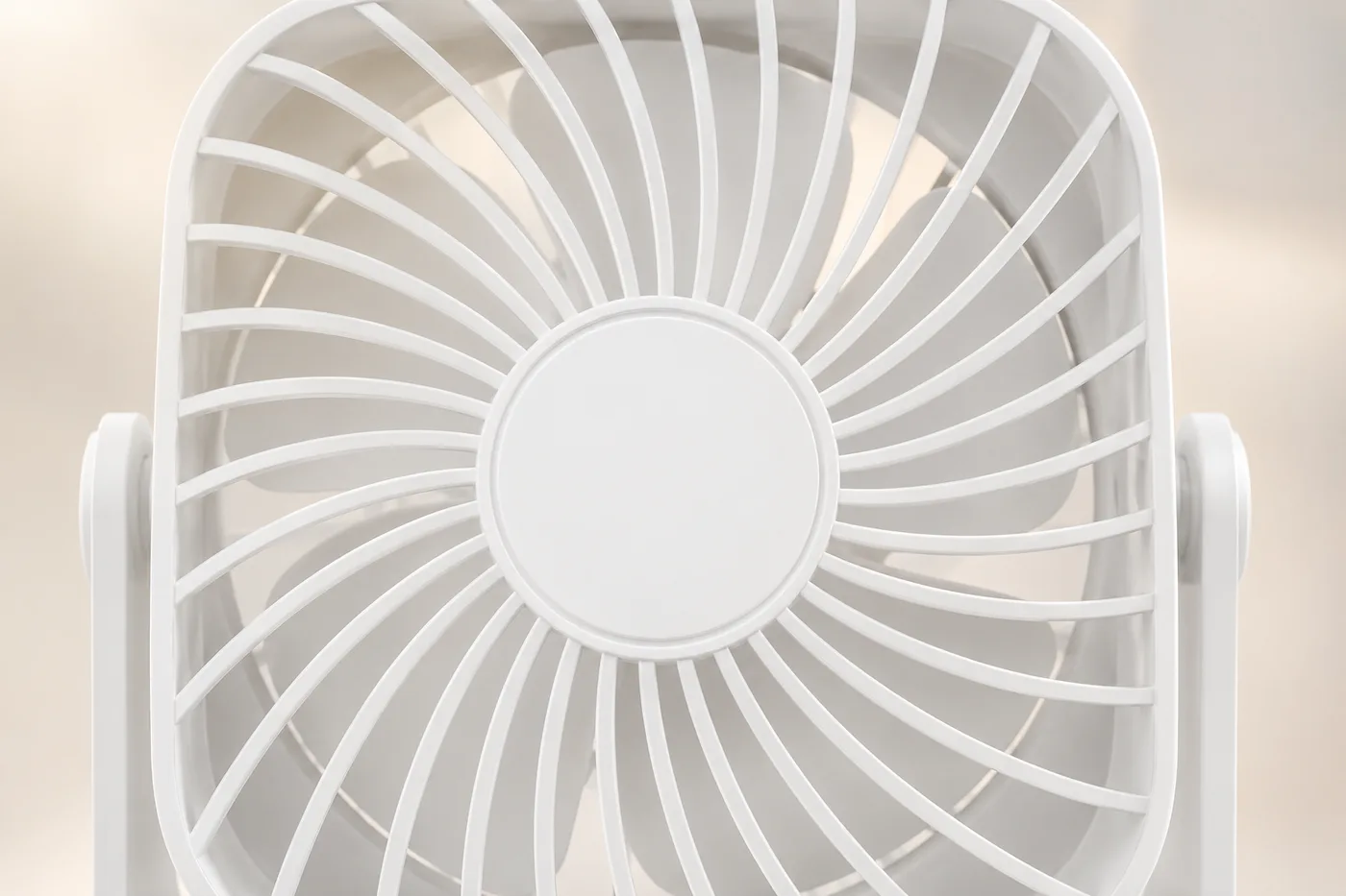 Gros plan sur la grille et l'hélice du petit ventilateur de bureau blanc